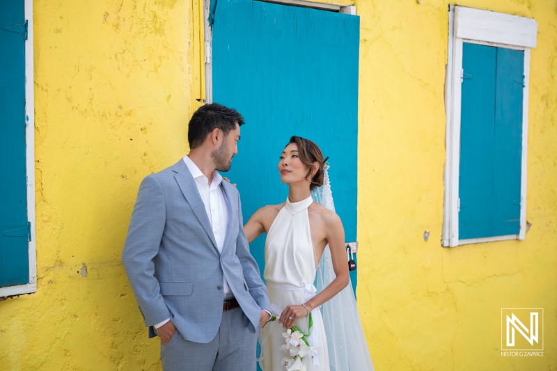 Couple exchanges vows at a wedding in Playa Hunku, Curacao surrounded by colorful buildings and vibrant scenery