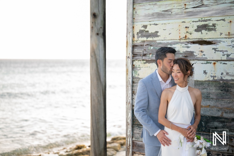 Couple stands together on their wedding day at Playa Hunku in Curacao near the ocean shore