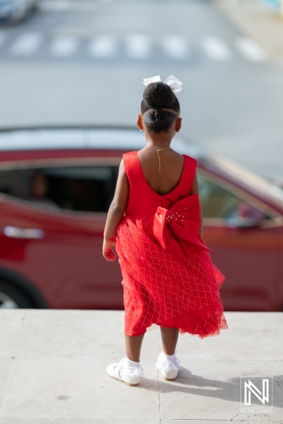 Beautiful child in a red dress standing outside during a wedding ceremony in Curacao, capturing the vibrant atmosphere and joyful moments