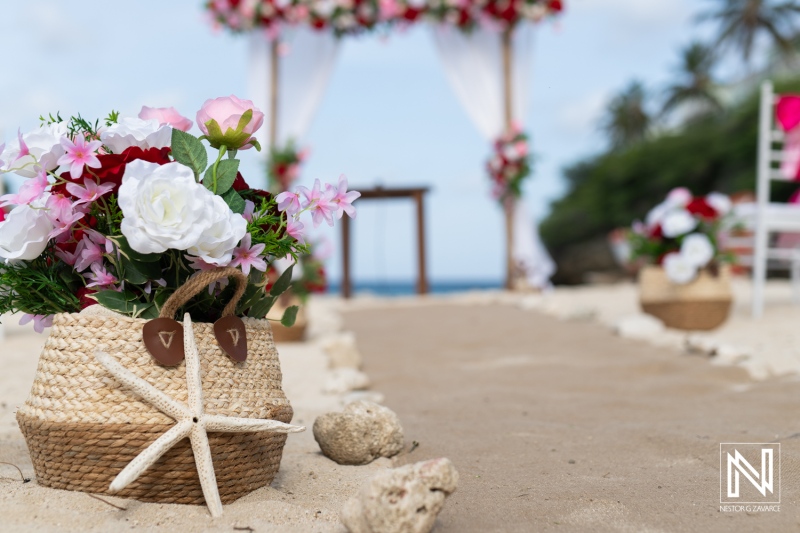 Beautiful Beach Wedding Setup With Floral Arrangements, a Decorated Arch, and Sandy Aisle Leading to the Ocean During a Sunny Day in a Tropical Paradise