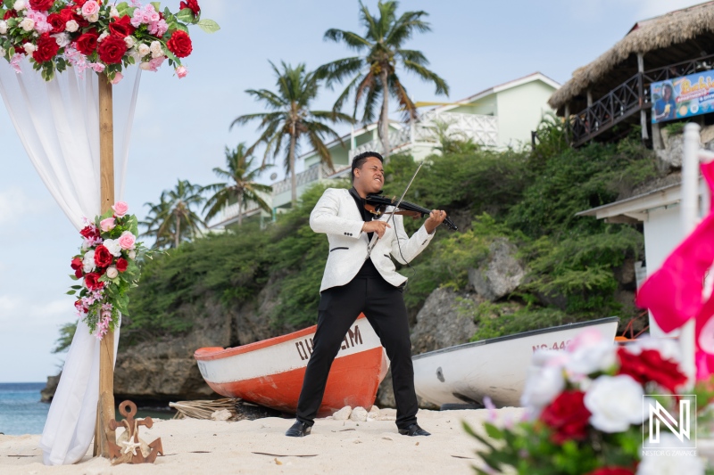 A Musician Plays the Violin on a Beach Surrounded by Vibrant Flowers and Tropical Scenery, Capturing a Moment of Joy and Celebration During a Sunny Day