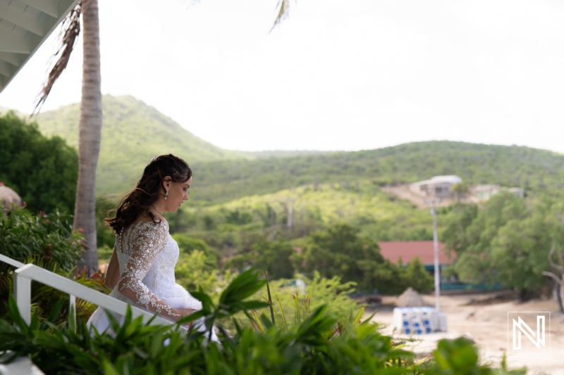 A Bride Enjoys a Serene Moment on the Terrace Surrounded by Lush Greenery and Mountains Before Her Beach Wedding Ceremony in a Tropical Paradise