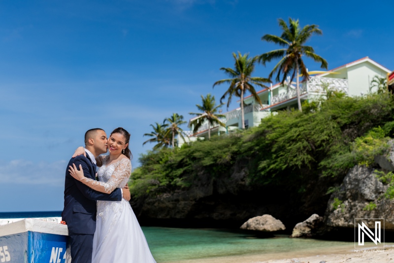 A Joyful Couple Celebrates Their Wedding on a Picturesque Beach With Palm Trees and Tropical Foliage Under a Bright Blue Sky