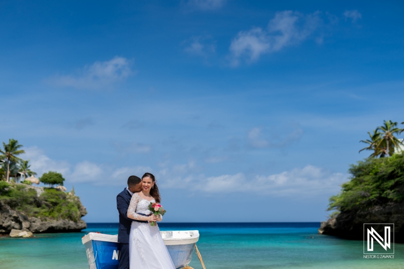 A Couple Celebrates Their Wedding Day on a Tranquil Beach by a Boathouse Under a Bright Blue Sky With Gentle Waves in the Distance