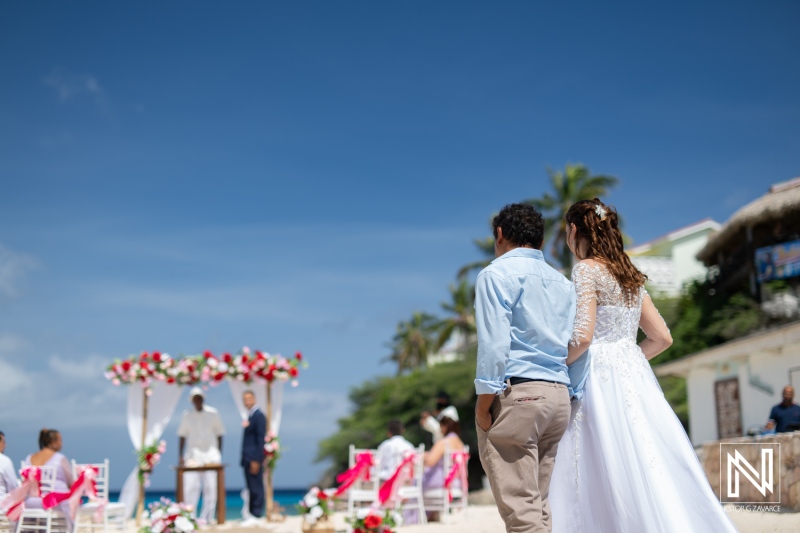 A Beautiful Beach Wedding Ceremony With Floral Decorations and Guests Enjoying the Sunny Day by the Ocean in a Tropical Paradise