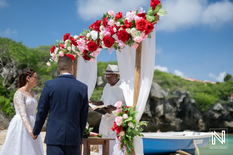 A Beautiful Beach Wedding Ceremony Taking Place Under a Flower-Adorned Arch in a Tropical Setting During the Daytime With a Couple Exchanging Vows