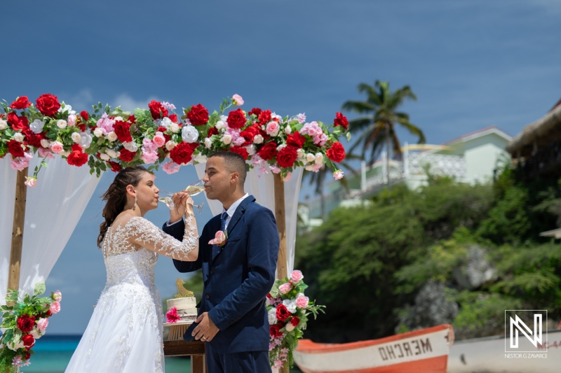 A Beautiful Beach Wedding Ceremony Takes Place Under a Floral Arch as a Couple Exchanges Vows, Surrounded by Tropical Scenery on a Sunny Day