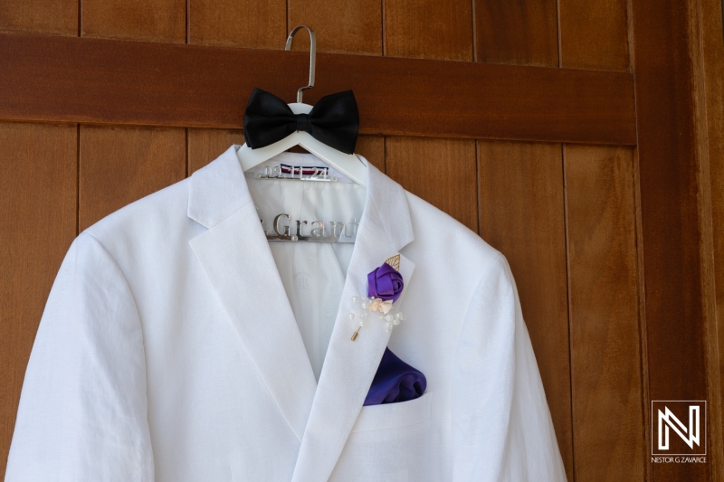 Elegant white tuxedo with bow tie and boutonniere hanging in a wooden display, perfect for a formal event or wedding celebration