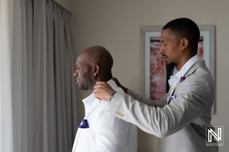 Groom prepares for wedding ceremony with best man\'s assistance in a bright hotel room during the morning hours