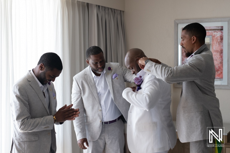 Groomsmen assisting the groom with his attire in an elegant hotel room before a wedding ceremony in the afternoon light