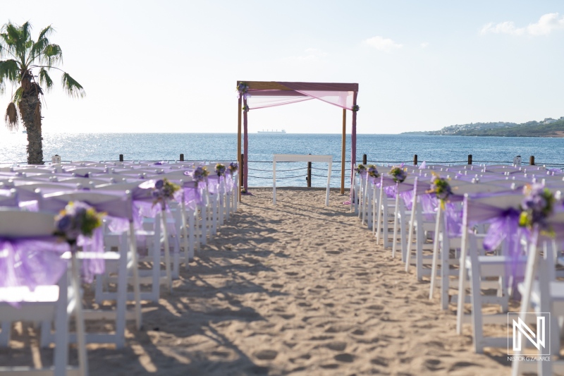 Beautiful beach wedding setup with purple decorations and chairs facing the ocean on a sunny day