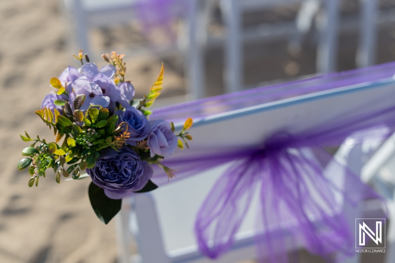 Beautiful floral decoration with purple accents at a beach wedding ceremony in the afternoon light