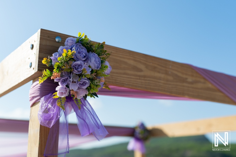 Beautiful floral arrangement adorning a wooden structure at an outdoor venue during a sunny day, perfect for a wedding celebration