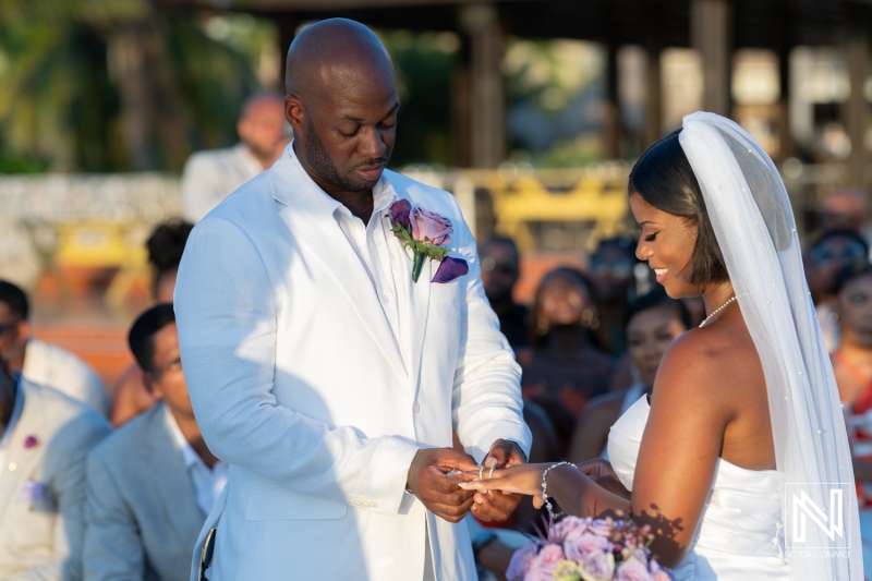 Couple exchanges wedding vows during an outdoor ceremony under the warm sun, surrounded by family and friends in a beautiful tropical setting