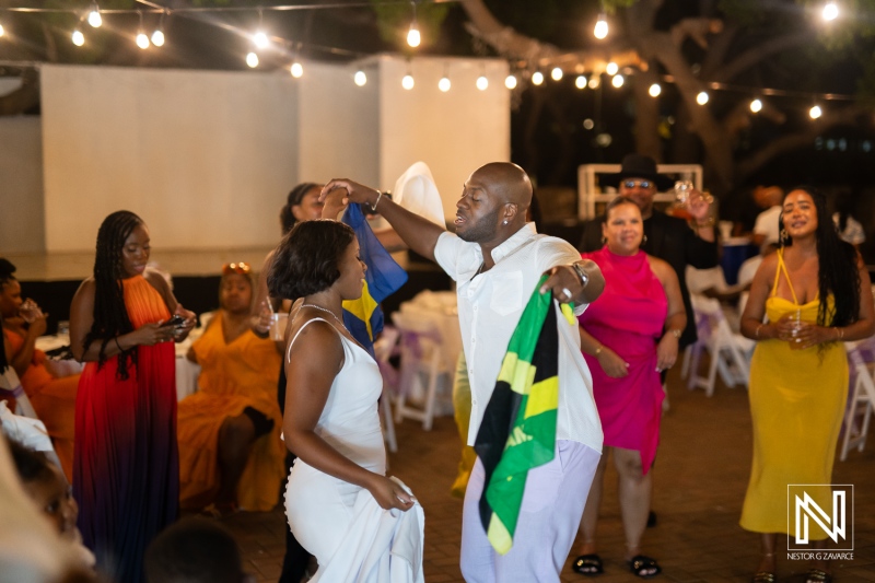 Dancing celebration with joyful guests in bright dresses at an outdoor event under twinkling lights during an evening gathering in a tropical setting