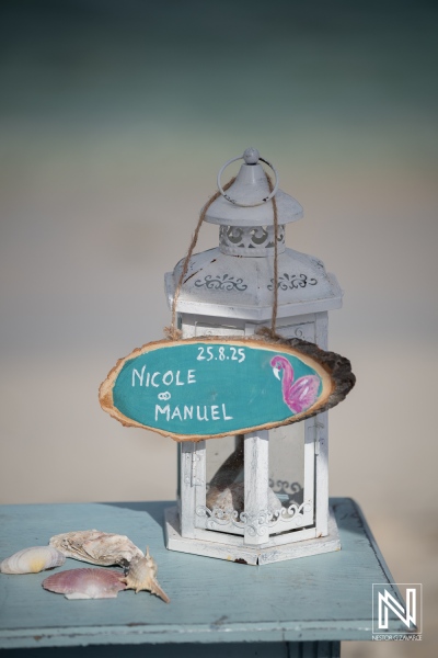 Wedding setup at Daaibooi Beach in Curacao with name sign and decorative lantern for Nicole and Manuel on August 25, 2025