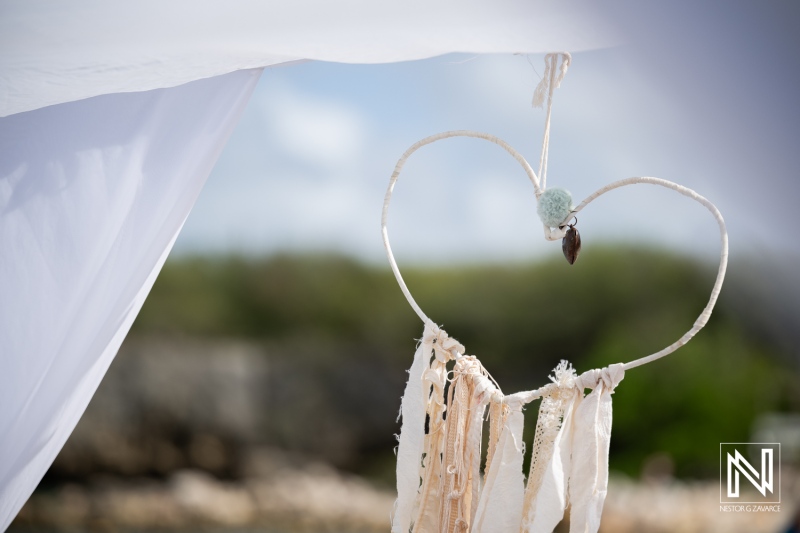 Wedding decorations at Daaibooi Beach in Curacao show a heart shape made with fabric and shells during a ceremony at The Kontiki Curacao Beach Resort