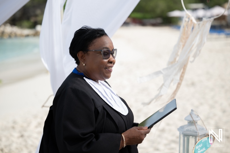 Wedding ceremony at Daaibooi Beach in Curacao with officiant in black robe