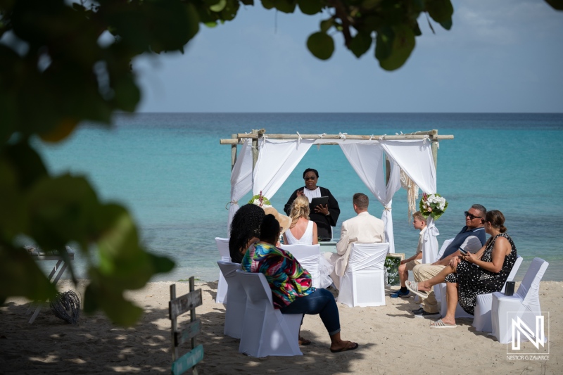 Wedding ceremony at Daaibooi Beach in Curacao with guests seating and a wedding arch