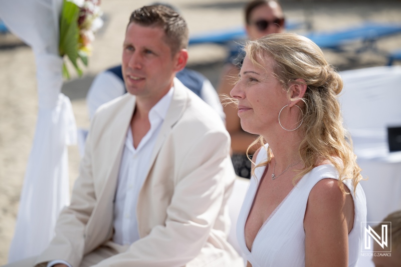 Wedding ceremony at Daaibooi Beach in Curacao near The Kontiki Curaçao Beach Resort with couple seated and guests present