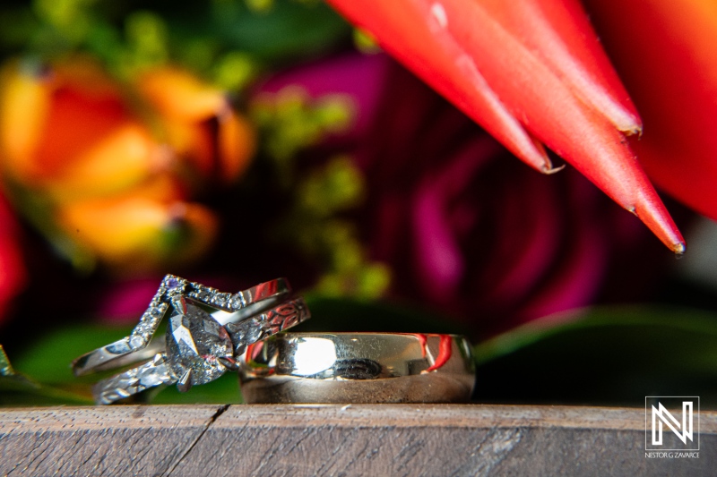 Wedding rings beautifully displayed amidst vibrant flowers at Kokomo Beach in Curacao during a sunset ceremony