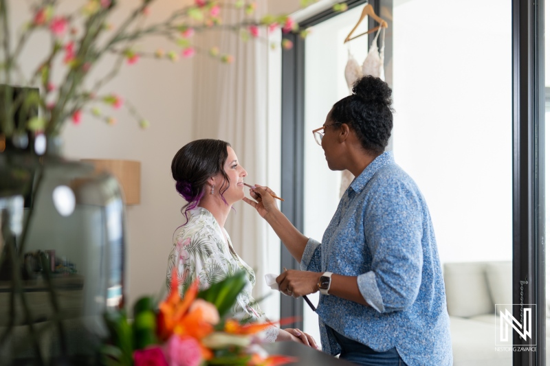 Bride getting ready at Kokomo Beach in Curacao for a beautiful wedding ceremony with makeup artist applying finishing touches
