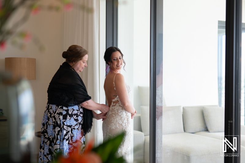 Bridal preparation at Kokomo Beach venue in Curacao for a beautiful wedding celebration with family moments captured behind glass