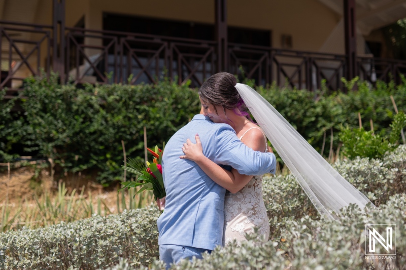 Couple embraces at their wedding ceremony on Kokomo Beach in Curacao during a sunny afternoon surrounded by lush greenery