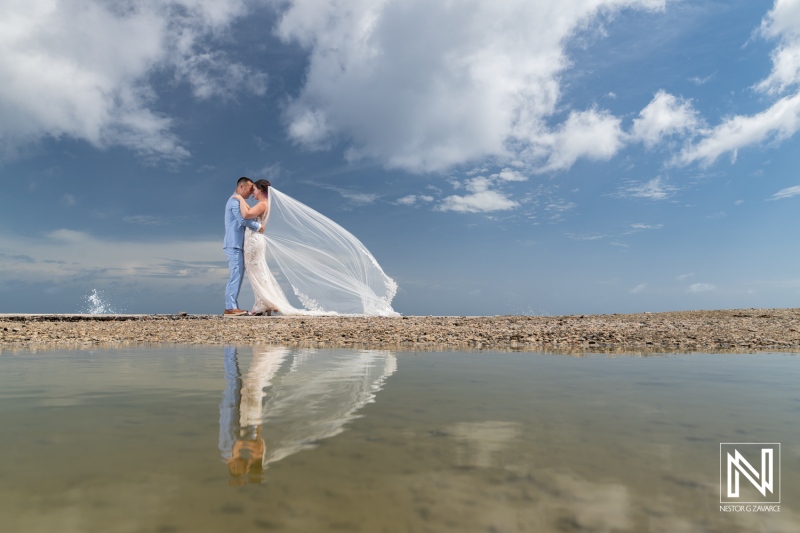 Couple shares intimate moment by the water during their wedding ceremony at Kokomo Beach in Curacao under a bright blue sky
