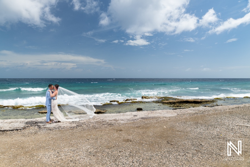 Couple embraces on the shore of Kokomo Beach in Curacao during their romantic wedding ceremony beneath a radiant sky
