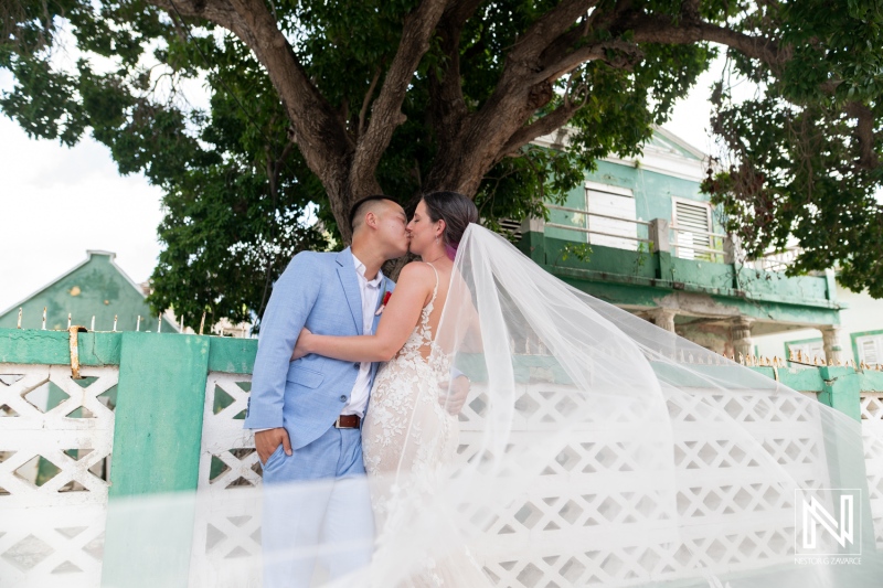 Couple shares a romantic kiss at their wedding celebration on Kokomo Beach in Curacao under a beautiful tree