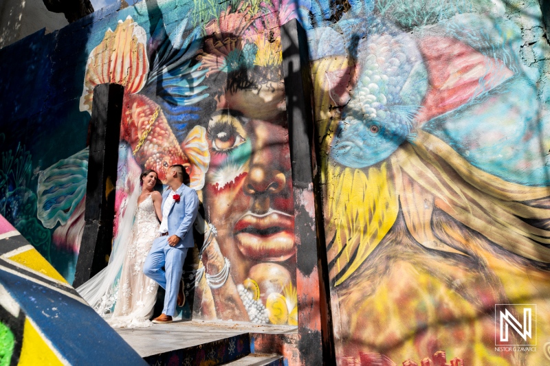 Couple celebrates love in front of vibrant mural at Kokomo Beach in Curacao during their wedding ceremony