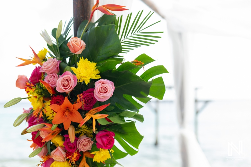 Colorful floral arrangement at a wedding ceremony on Kokomo Beach in Curacao with ocean backdrop and white decorations