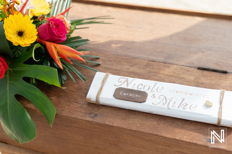Wedding celebration at Kokomo Beach in Curacao featuring a personalized sign and vibrant floral arrangement