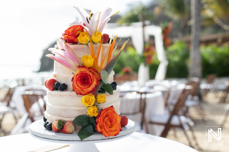 Elegant wedding cake adorned with vibrant flowers at Kokomo Beach in Curacao during a beautiful seaside ceremony