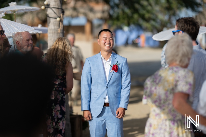 Groom smiles joyfully during wedding ceremony at Kokomo Beach in Curacao under the warm sun