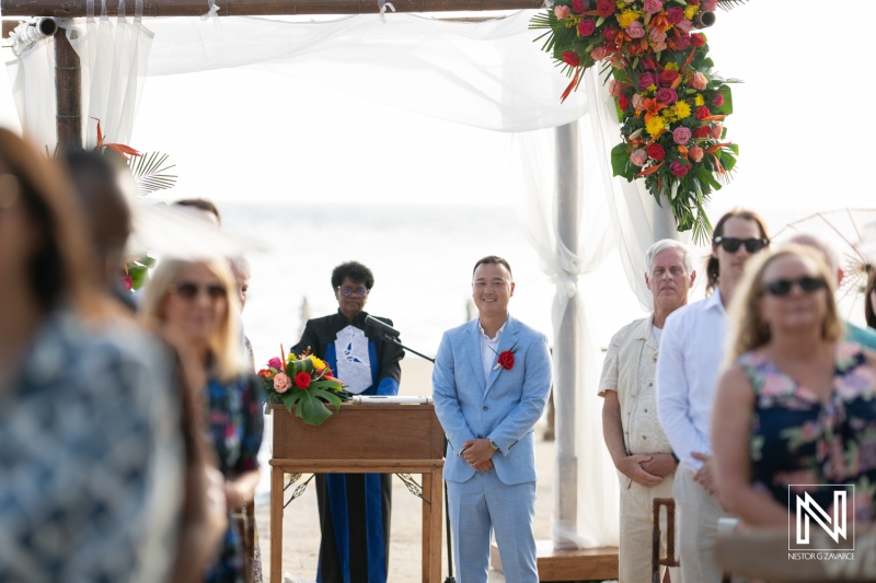Wedding ceremony at Kokomo Beach in Curacao with guests gathered and a joyful groom awaiting his bride