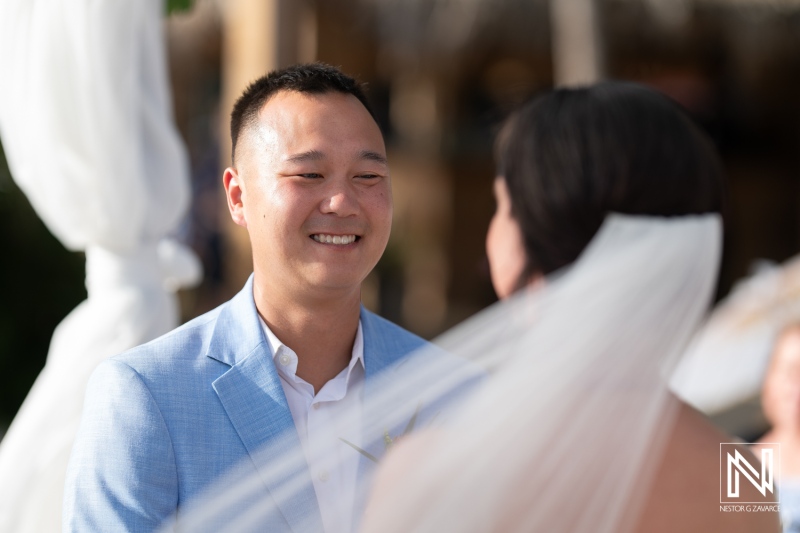 Wedding ceremony at Kokomo Beach in Curacao celebrating love with a joyful couple exchanging vows under a beautiful blue sky and driftwood decor