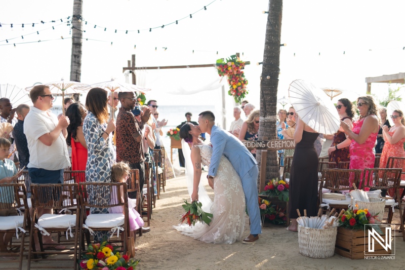 Ceremony at Kokomo Beach in Curacao, where the couple exchanges vows amidst cheering friends and family, creating lasting memories in paradise