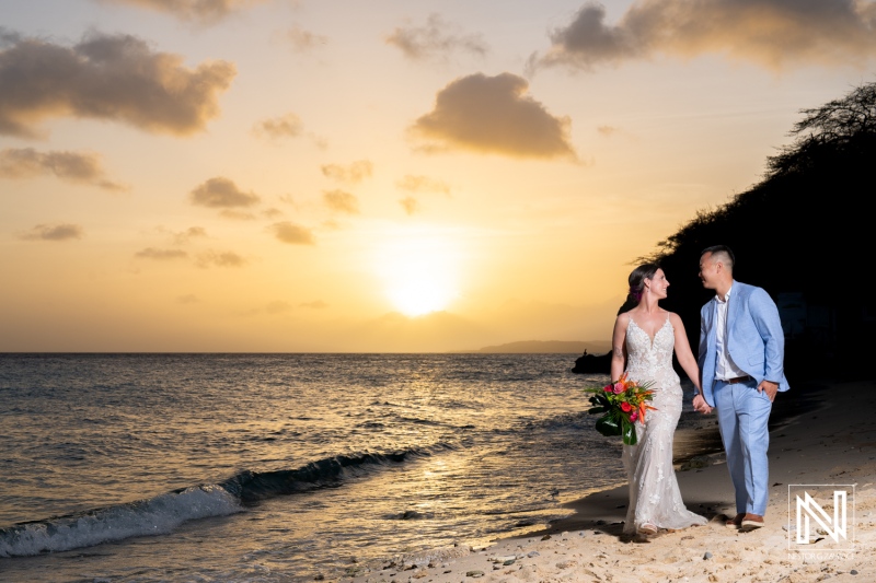 Couple enjoys a romantic walk along Kokomo Beach during their wedding ceremony in Curacao at sunset