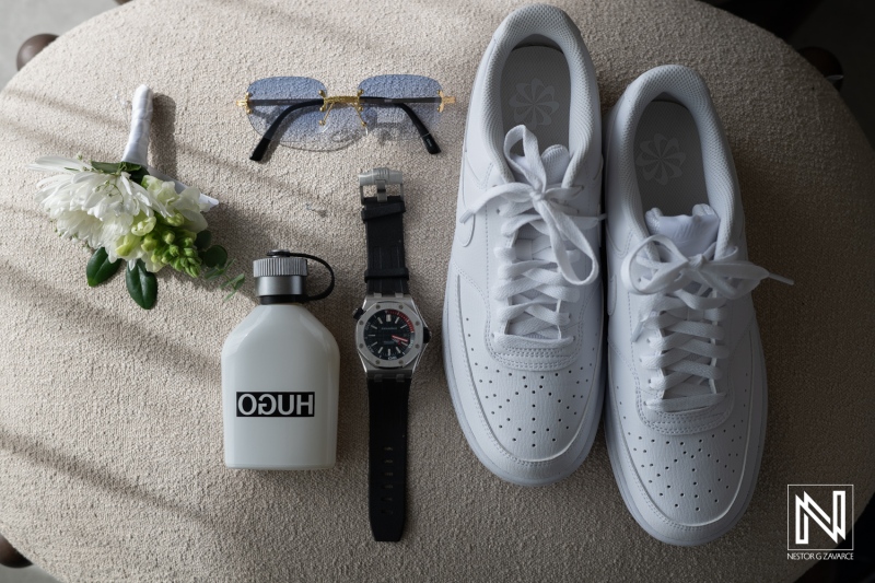 Casual fashion setup featuring white sneakers, stylish accessories, and a water bottle arranged on a neutral surface in a well-lit room