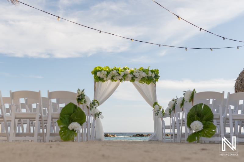 Beautiful beach wedding setup with elegant floral arch and chairs arranged for the ceremony under a clear sky on a sunny day