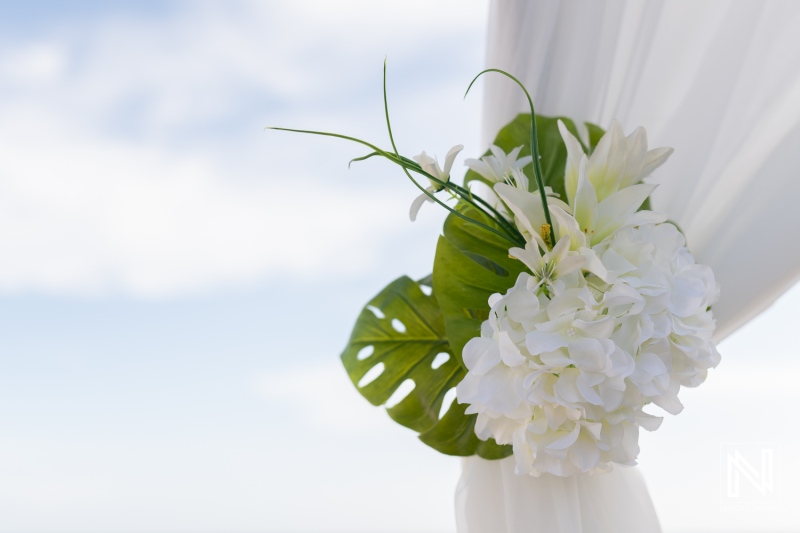 Beautiful floral arrangement with white flowers and green leaves at a serene outdoor wedding venue during daytime