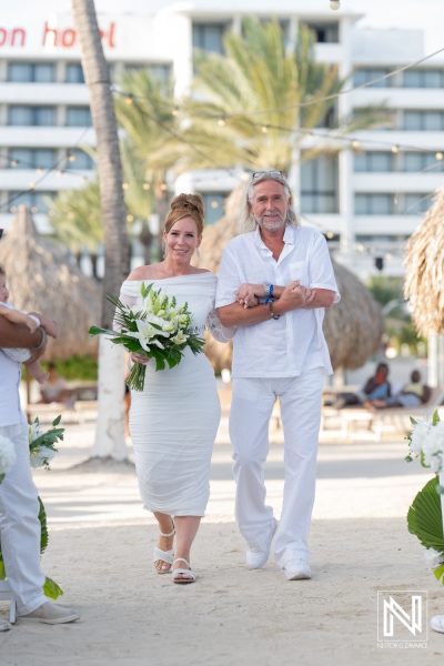 A joyful bride walks down the sandy aisle with her father in a beachfront wedding at a tropical resort under the golden sun