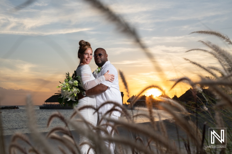 A beautiful sunset wedding ceremony by the beach in a tropical destination with a couple embracing each other joyfully as the day ends