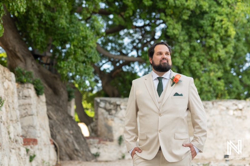 Groom stands confidently in a stunning courtyard at the Dreams Curacao Resort during a beautiful wedding ceremony