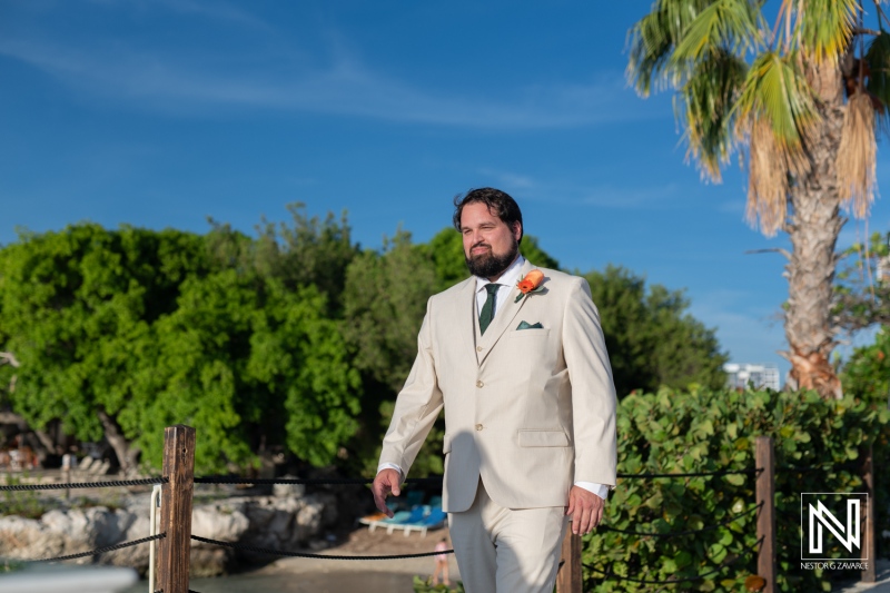 Groom walking confidently at a wedding venue in Curacao surrounded by lush greenery and beautiful coastal views