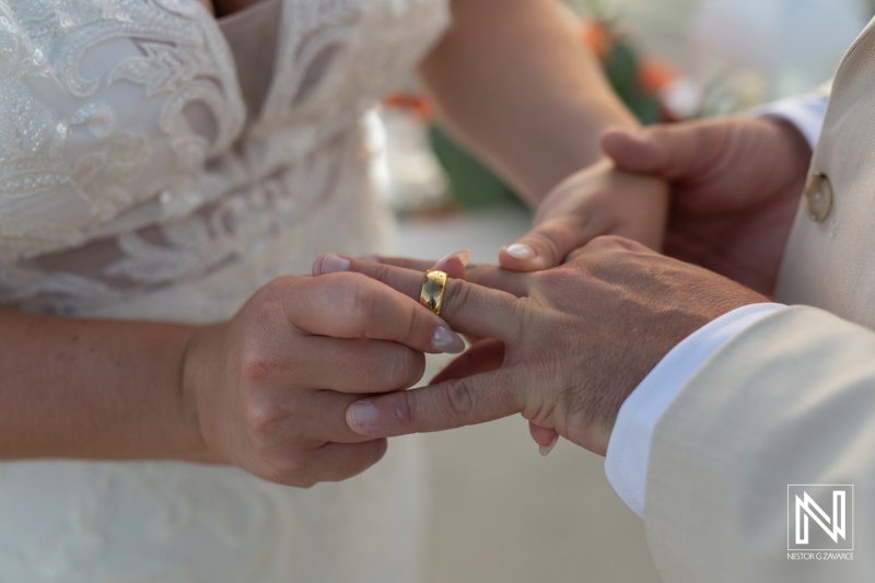 Couple exchanges wedding rings during a romantic ceremony in Curacao at Dreams Curacao Resort with a beautiful backdrop