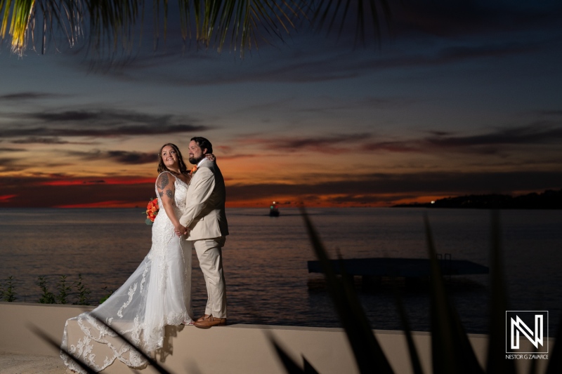 Couple celebrates their wedding at Dreams Curacao Resort during a stunning sunset by the Caribbean Sea