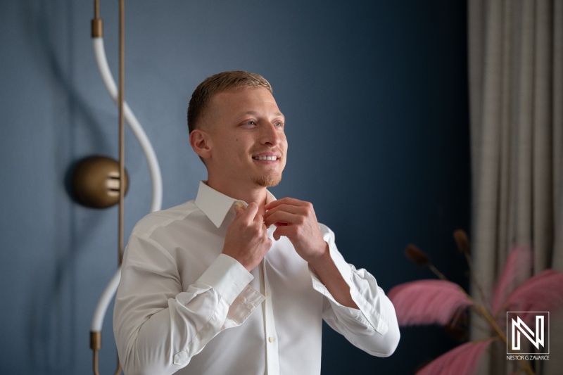 Groom prepares for wedding at Renaissance Wind Creek Curacao Resort with focused expressions and final touches
